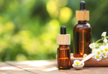 Ahşap masa üzerinde papatya uçucu yağ ve çiçek Şişeleri, metin için alan