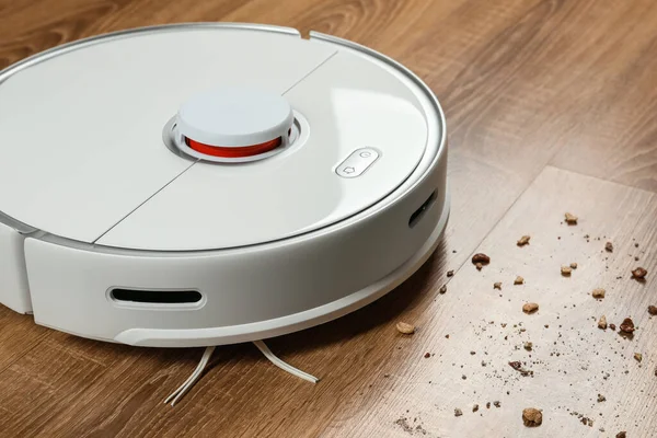 stock image Robotic vacuum cleaner removing dirt from wooden floor indoors, closeup