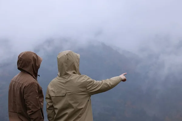 山の景色を楽しむレインコートの男と女 — ストック写真