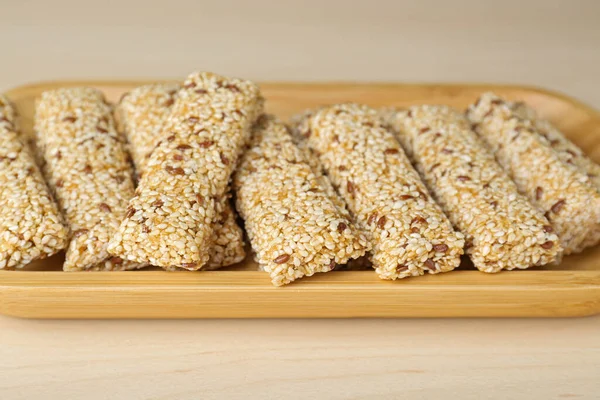 stock image Plate with tasty sesame seed bars on wooden table, closeup