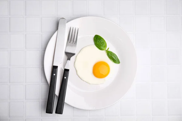 Вкусное Жареное Яйцо Базиликом Тарелке Белом Плиточном Столе Вид Сверху — стоковое фото