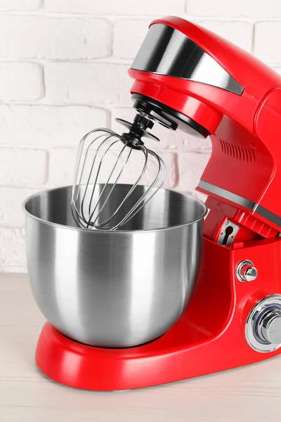 Modern red stand mixer on white wooden table