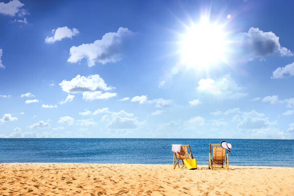 Empty wooden sunbeds on sandy beach near sea on sunny day