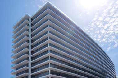 Exterior of residential building with balconies against blue sky, low angle view