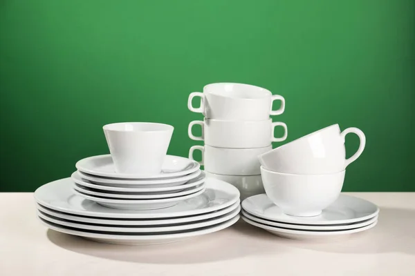 Yeşil Arkaplana Karşı Beyaz Masada Temiz Bulaşık Takımı — Stok fotoğraf