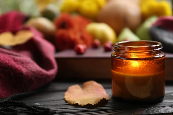 stock image Burning scented candle and book on wooden table, space for text. Autumn season