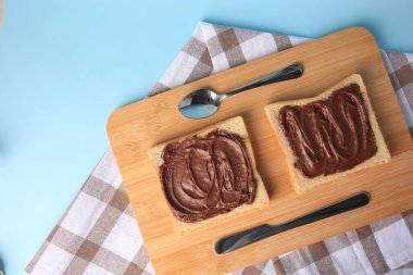 Açık mavi arka planda servis edilen çikolata ezmeli lezzetli tostlar, üst manzara. Metin için boşluk