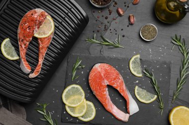 Somon pişiriyorum. Izgara, taze balık bifteği, limon ve baharatlar karanlık masada, düz yerde.