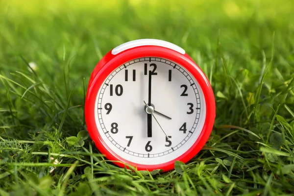 屋外の緑の芝生の上の赤い目覚まし時計 — ストック写真