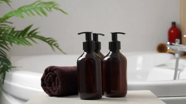 stock image Bath foam and other personal hygiene products in bottles and rolled towel on small table in bathroom