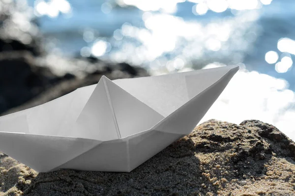 White paper boat on rock near sea, closeup