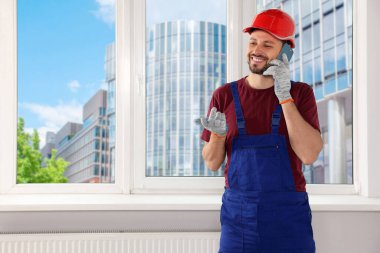 Üniformalı profesyonel tamirci içeride telefonla konuşuyor, mesaj için yer var.