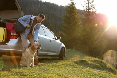 Mutlu adam ve sevimli köpek dağlarda arabanın yanında. Evcil hayvanla seyahat etmek