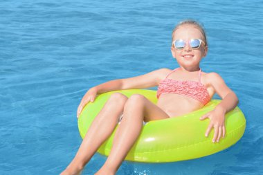 Güneşli bir günde denizde şişme yüzüğü olan mutlu küçük kız.