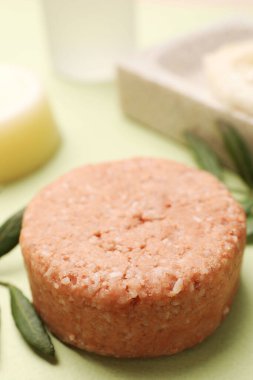 Yeşil arka planda sağlam şampuan barı ve yaprak, yakın plan. Saç bakımı