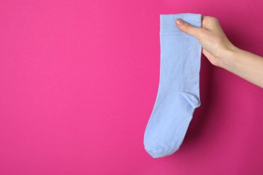 Açık pembe arka planda açık mavi çorap tutan kadın, yakın plan. Metin için boşluk