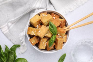 Lezzetli kızarmış tofu, fesleğen ve susam tohumlarıyla dolu bir kâse.