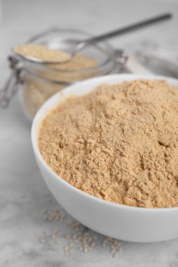 Beyaz mermer masada seramik kasede susam unu, yakın plan.