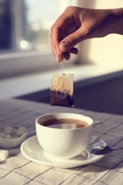 Kadın çay poşetini dışarı çıkarıyor. Kapalı bir masada, yakın plan.