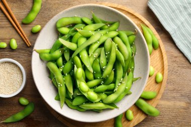 Tahta masada susam tohumlarıyla servis edilen kabuklu yeşil edamame fasulyeleri.