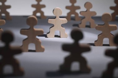 İşe alım ve işe alım konsepti. Masadaki diğer insanlar arasında ışık huzmesindeki insan ahşap figür