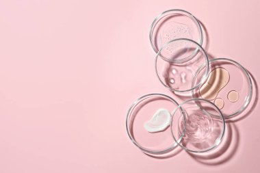 Pembe arka planda kozmetik numuneleri olan bir sürü Petri kabı var. Metin için boşluk