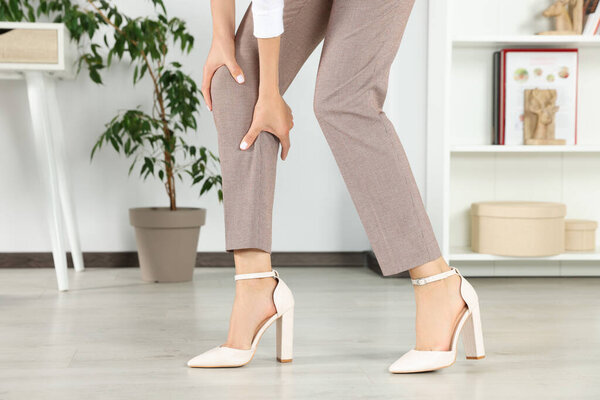 Женщина трёт больную ногу дома, крупным планом