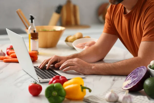 Mężczyzna Robi Obiad Podczas Oglądania Online Gotowania Kurs Pomocą Laptopa — Zdjęcie stockowe