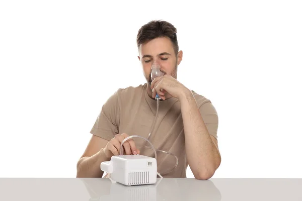 stock image Sick man using nebulizer for inhalation at table on white background