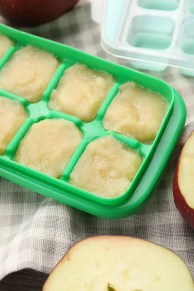 Apple puree in ice cube tray with ingredients on table, closeup