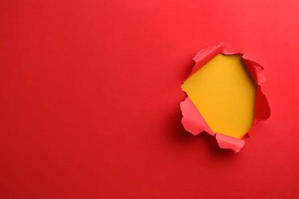 stock image Hole in red paper on yellow background, space for text