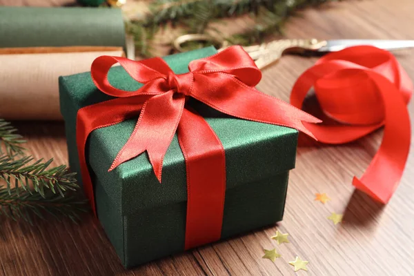 美しいクリスマスギフトボックス紙に包まれ 木製のテーブルの上に赤い弓で飾られ クローズアップ — ストック写真