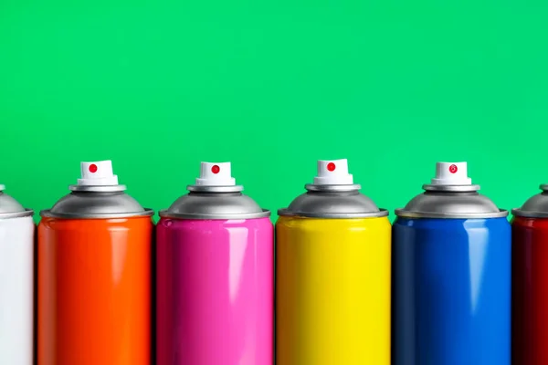 stock image Colorful cans of spray paints on green background