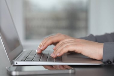Masada dizüstü bilgisayarda yazan bir kadın, yakın plan. Elektronik belge yönetimi