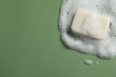 Yeşil arka planda sabun ve kabarık köpük, üst manzara. Metin için boşluk