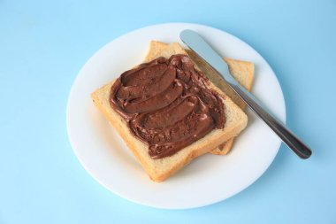 Açık mavi arka planda çikolata ezmeli lezzetli tost.