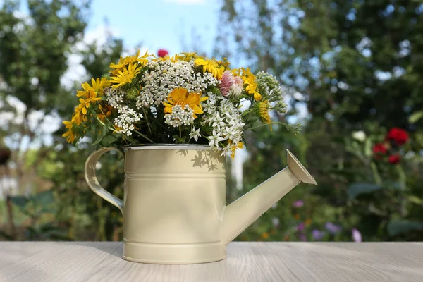 stock image Beautiful bouquet of bright wildflowers in watering can on white wooden table outdoors