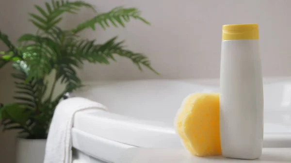 Stock image Bottle with foam bath and sponge on small table in bathroom, space for text