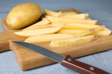 Whole and cut potatoes with knife on grey wooden table, closeup. Cooking delicious french fries clipart