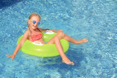 Güneşli bir günde havuzda şişme yüzük takan tatlı küçük kız.