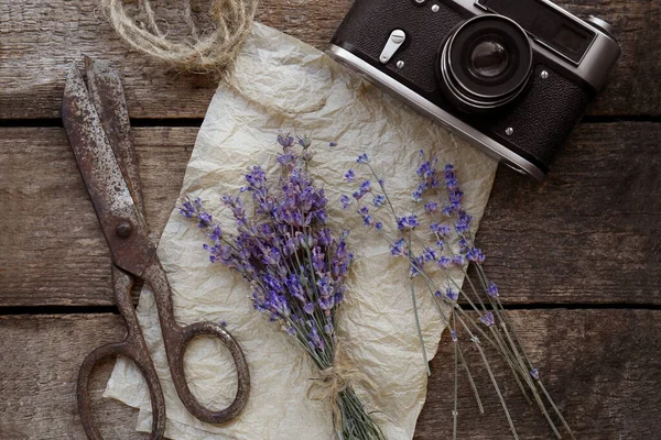 Beautiful lavender flowers, vintage camera and scissors on wooden table, flat lay