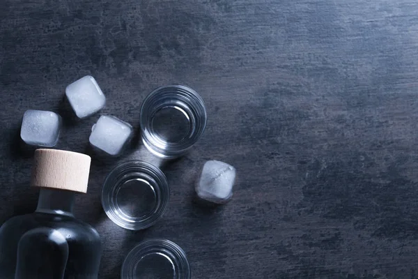 ウォッカのボトルと暗いテーブルの上に氷とショットグラス フラットレイアウト テキストのスペース — ストック写真