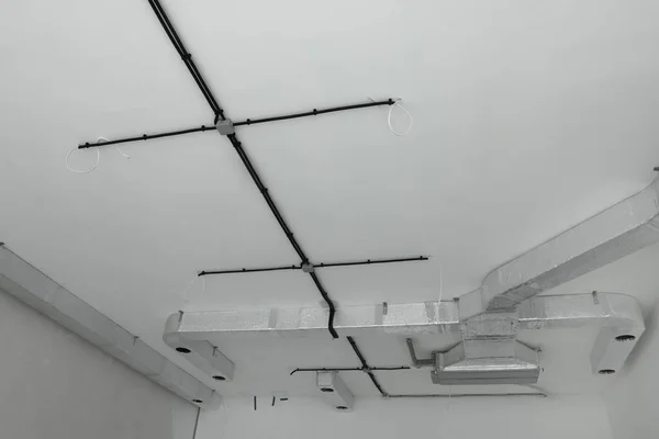 白色天花板上的黑色电缆和通风系统 — 图库照片
