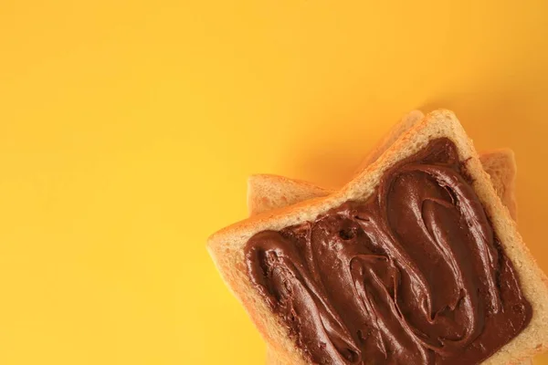 Tasty toast with chocolate paste on yellow background, top view. Space for text