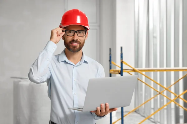Professional engineer in hard hat with laptop indoors