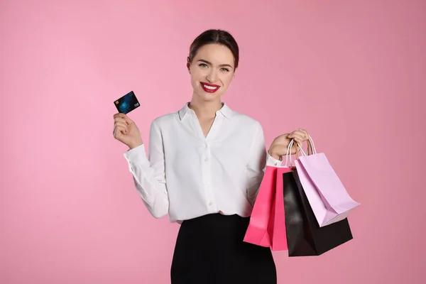 明るいピンクの背景にショッピングバッグやクレジットカードで幸せな若い女性 大販売 — ストック写真