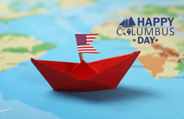 Happy Columbus Day. Red paper boat with American flag on world map