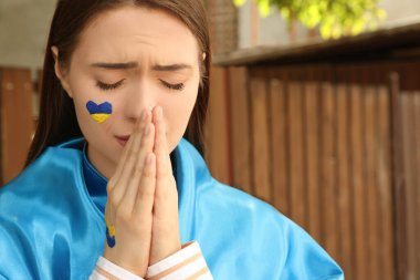 Yüzüne Ukrayna bayrağı çizen üzgün genç bir kadın, yakın plan. Metin için boşluk