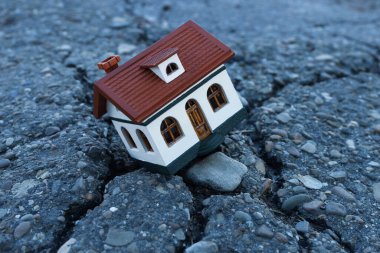 Çatlak asfaltta ev modeli. Deprem felaketi