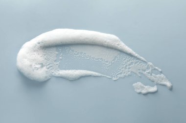 Smudge of white washing foam on color background, top view clipart